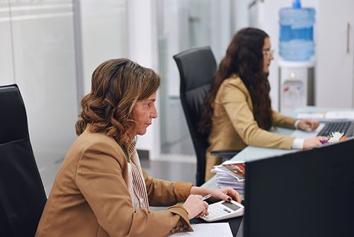 Dos mujeres trabajando con calculadora y computadora